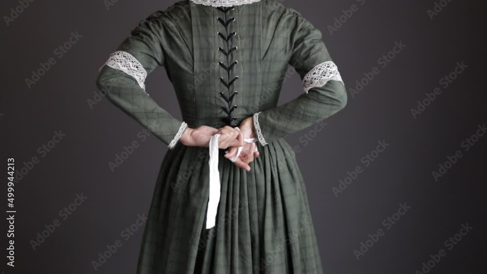 A Victorian working class woman or maid servant tying her apron A Victorian working class woman or maid servant tying her apron
