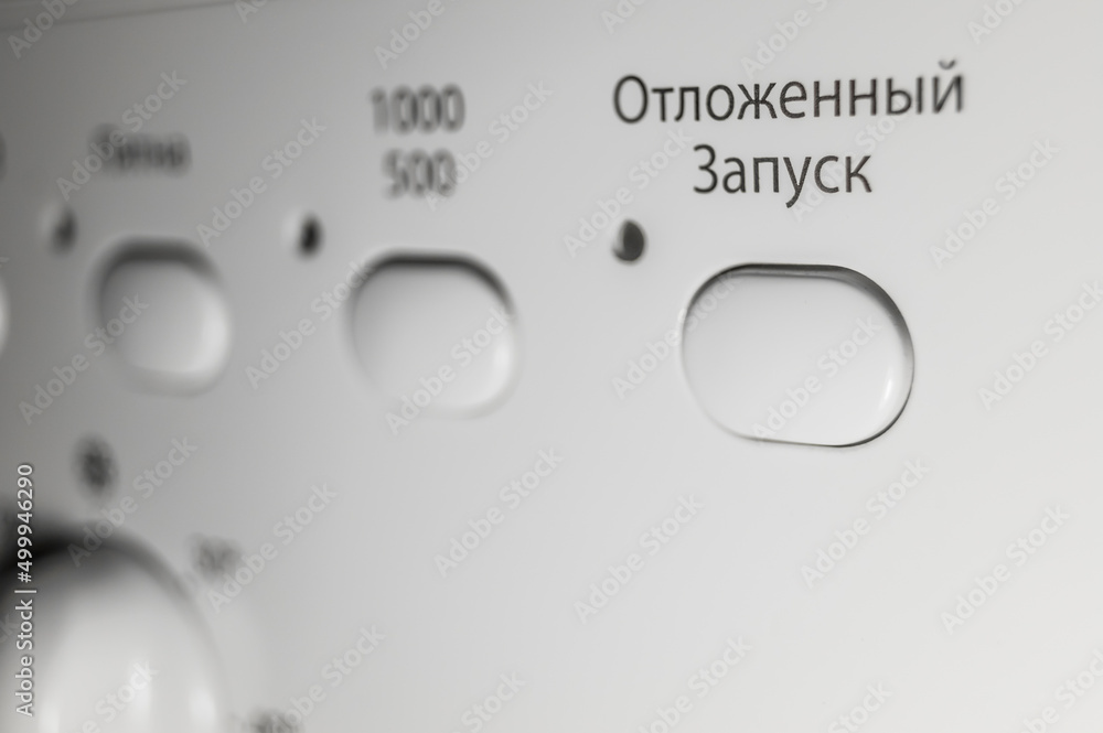 Button to turn on the function of delayed start of washing. Control panel of the washing machine. Russian interface. Selective focus. Text to translate Russian - Delayed Startup Button to turn on the function of delayed start of washing. Control panel of the washing machine. Russian interface. Selective focus. Text to translate Russian - Delayed Startup