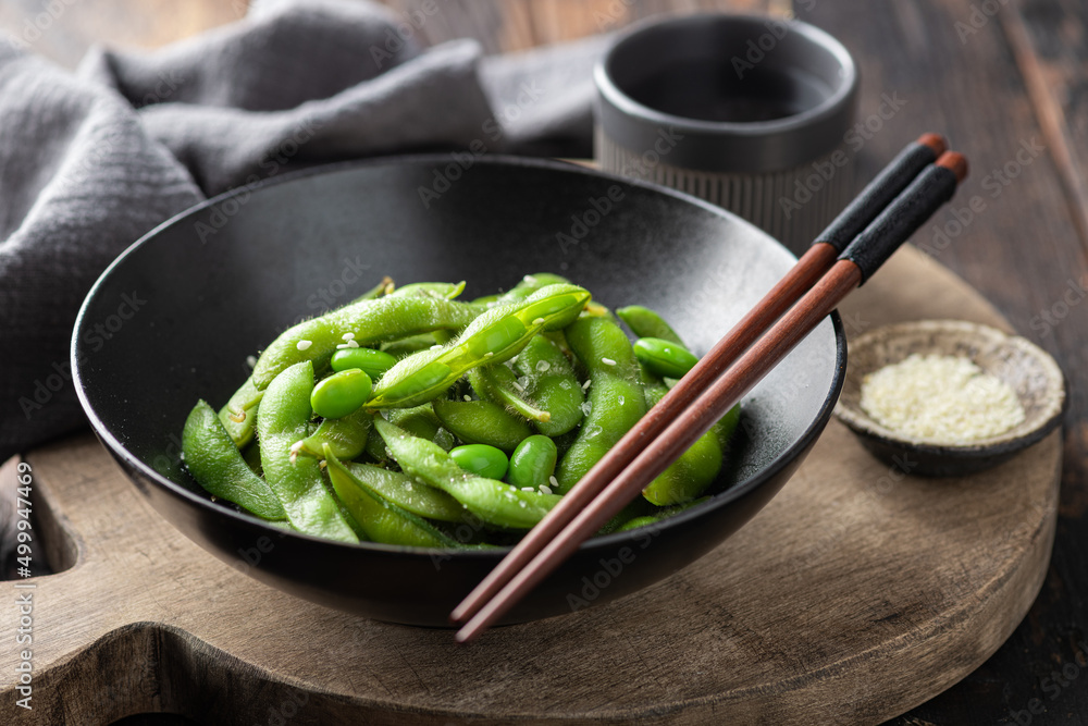 steamed edamame beans in a black ceramic bowl, soybeans, selective focus