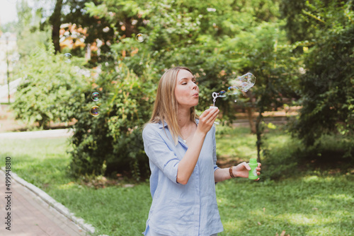 young woman blowing bubbles in the park and having fun