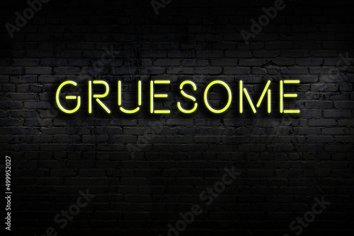 Neon sign. Word gruesome against brick wall. Night view photo