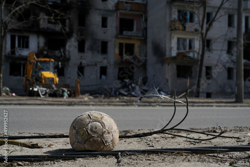 A children's soccer ball lies near the road against a building destroyed by an explosion in the war in Ukraine. Nearby are the wires of a broken power line.