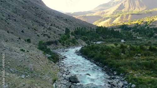 Aerial drone of a glacier river flowing through the mountains of Astore Valley in Pakistan during a sunset afternoon in the summer photo