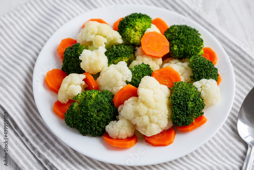 Mixed Organic Steamed Vegetables (Carrots, Broccoli and Cauliflower) on a Plate on a white wooden background, low angle view.