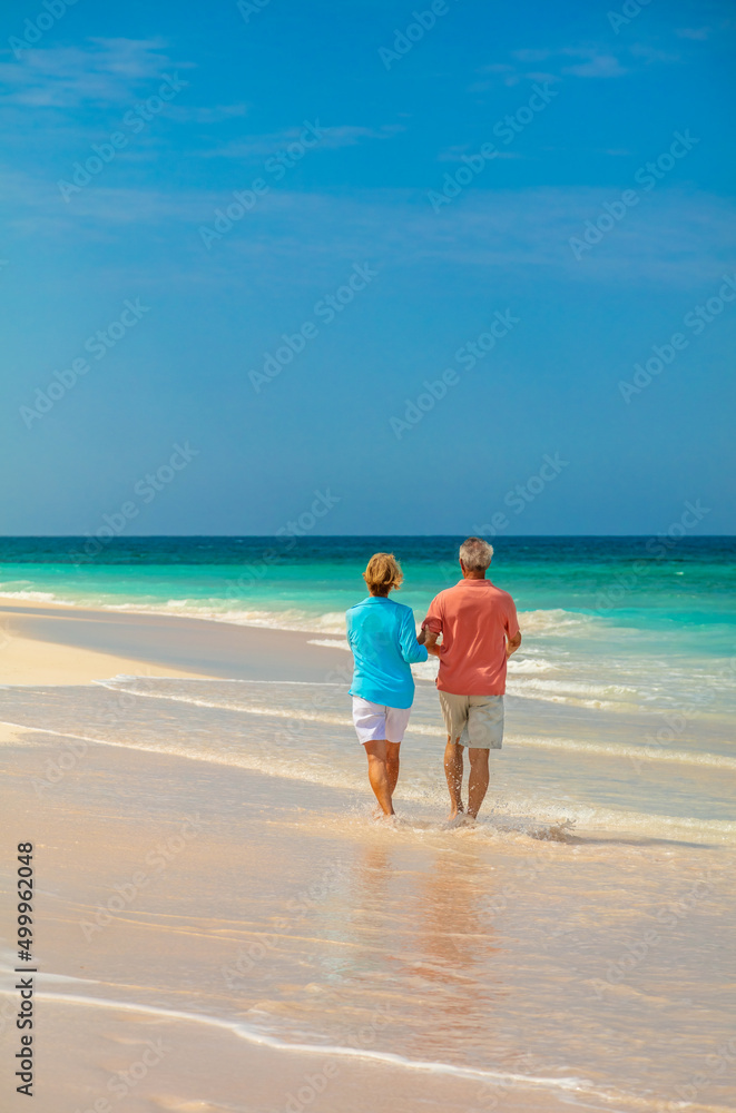 Mature couple walking along shoreline of tropical beach
