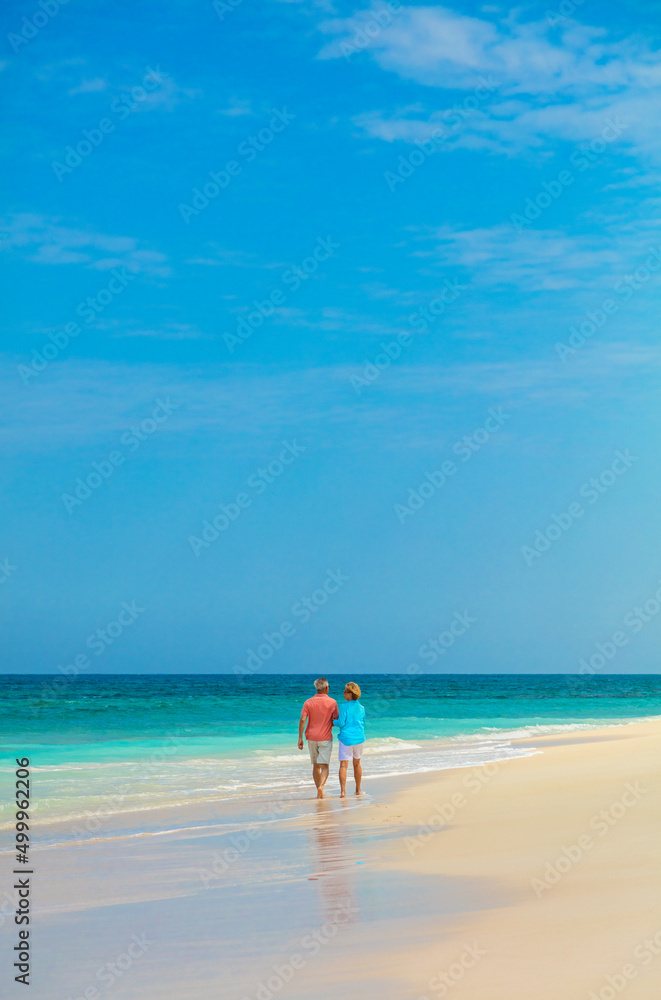 Paradise island view with mature couple walking together