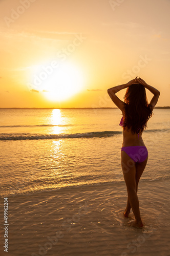 Young Asian female watching sunrise on ocean horizon