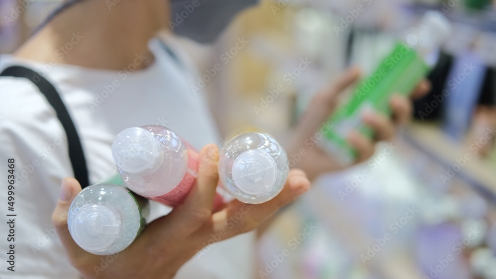 Buying cosmetics in an eco store. The buyer in the store examines the proposed product, reads information about the goods on it. In his right hand he holds the prepared goods for purchase. Buying cosmetics in an eco store. The buyer in the store examines the proposed product, reads information about the goods on it. In his right hand he holds the prepared goods for purchase.
