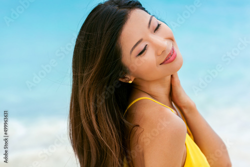 Attractive Asian girl smiling enjoying relaxing beach vacation