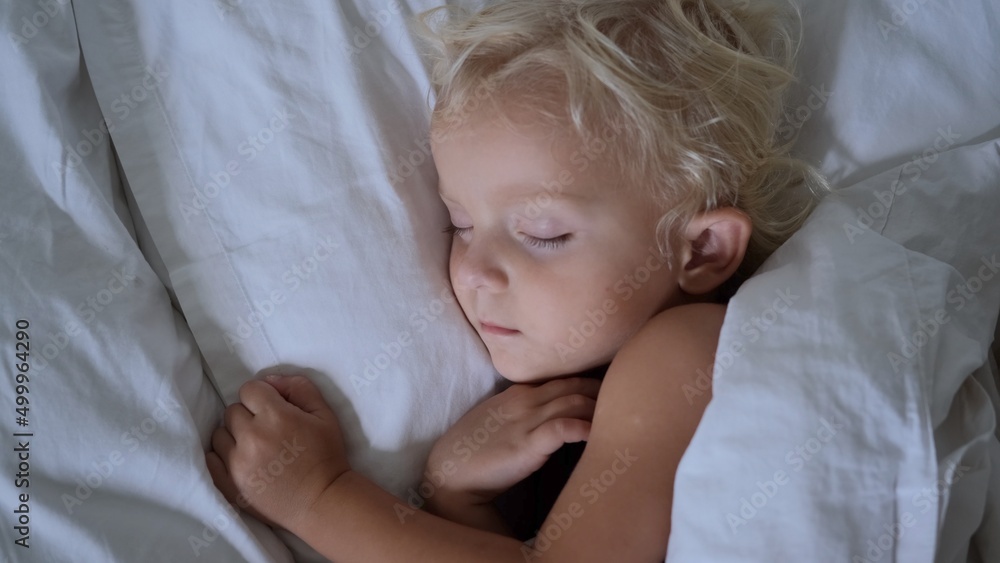 Healthy baby sleep. A laid-down blonde baby of two years in bed. Sleep alone in a separate room. Her sleep directly plays an important role in the process of restoring physical and mental energy. Healthy baby sleep. A laid-down blonde baby of two years in bed. Sleep alone in a separate room. Her sleep directly plays an important role in the process of restoring physical and mental energy.
