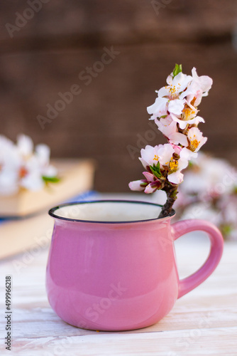 close up beautiful blossom twig of almond tree in a pink cup on the table. spring still life