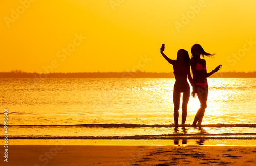 Silhouette of girls taking selfie with ocean sunrise
