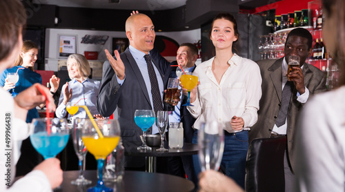 Smiling man enjoying conversation with young female colleague on corporate party in bar