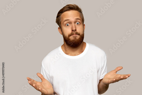 Quadro em tela Horizontal picture of confused young bearded man standing and shrugging over gre