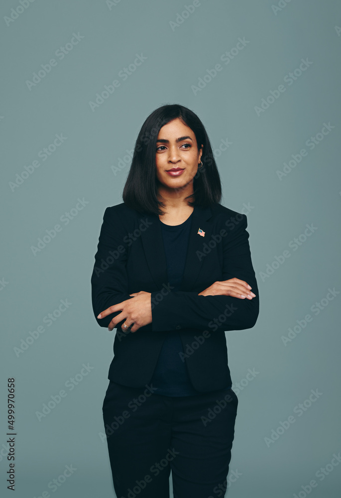 Pensive congresswoman standing with her arms crosed in a studio Pensive congresswoman standing with her arms crosed in a studio