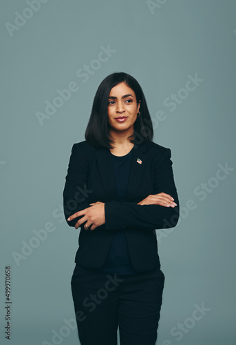 Pensive congresswoman standing with her arms crosed in a studio photo