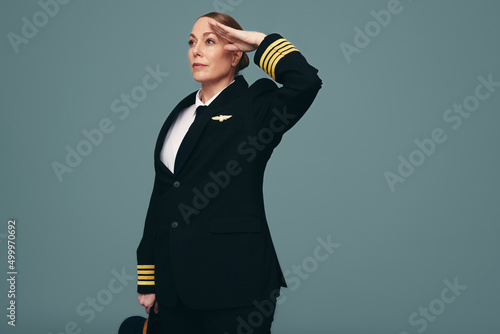 Professional pilot saluting while standing in a studio photo