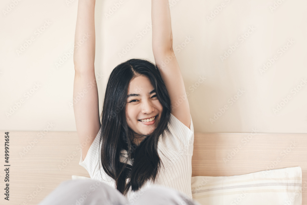 Portrait of young adult asian pretty woman in bedroom stretching arm after wake up Portrait of young adult asian pretty woman in bedroom stretching arm after wake up