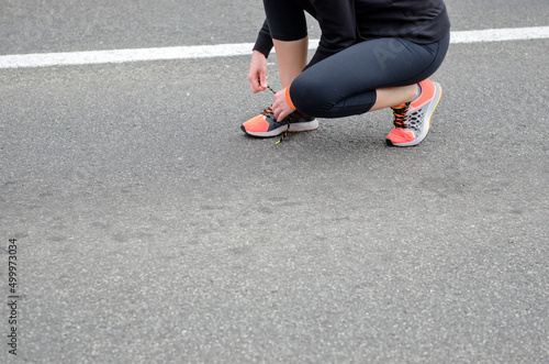 Runner lacing shoes before workout, women in running shoes and sportswear, active healthy lifestyle and sport concept 
