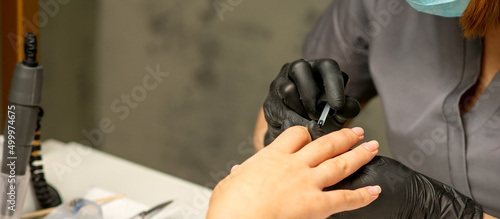 Manicure painting process. Manicure master paint the nails with transparent varnish in a nail salon  close up