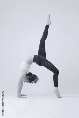 Black and white serie of photos of young fit woman practising yoga. Studio shot on white background.