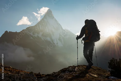 Obraz Mountain Man with backpack hiking in the mountains at sunset