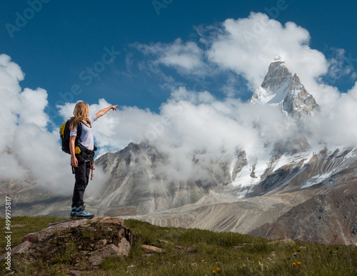 Woman hiking in mountains and pointing to a beautiful mountain summit in Indian Himalayas 