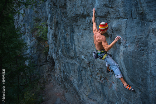 Powerful rock climber climbing on an overhanging rock face outdoors 