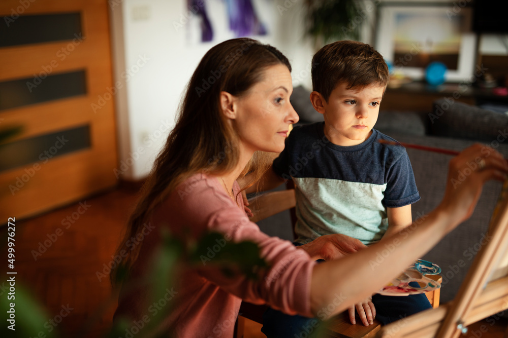 Obraz premium Mother and son painting at home. Little boy drawing with mom in living room..