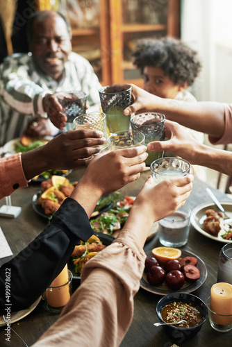 Close-up of family toasting with glasses of drinks while sitting at dining table during dinner