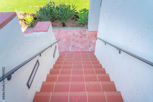 Stairs with red tile steps heading to the red stone pavement downstairs photo