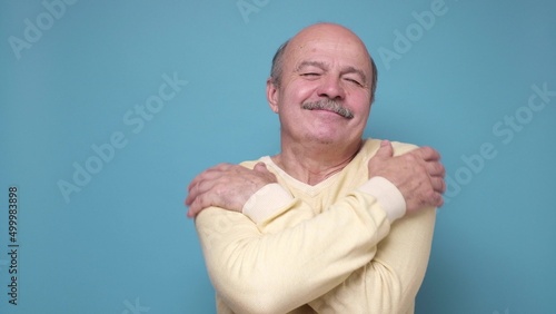 Senior handsome man hugging himself happy and positive, smiling confiden photo