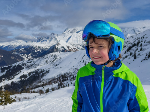Face portrait of happy young boy in ski or snowboard outfit