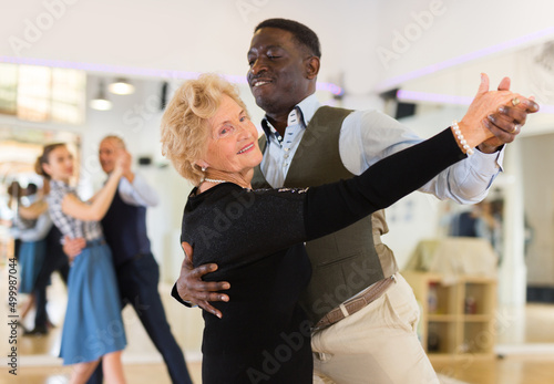 Stampa su tela Elderly woman learning ballroom dancing in pair in dance studio