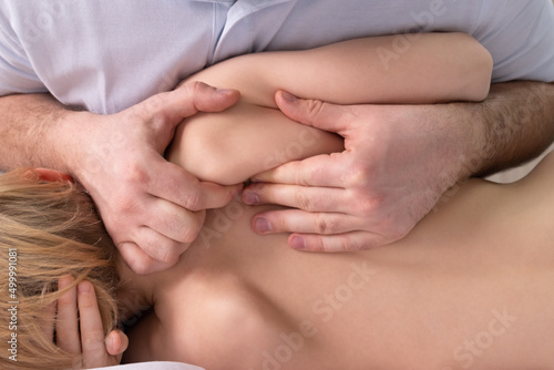 The osteopath works with a spatula. Back view. The teenage child lies on its side. The chiropractor works with the area of the thoracic region. Posture correction