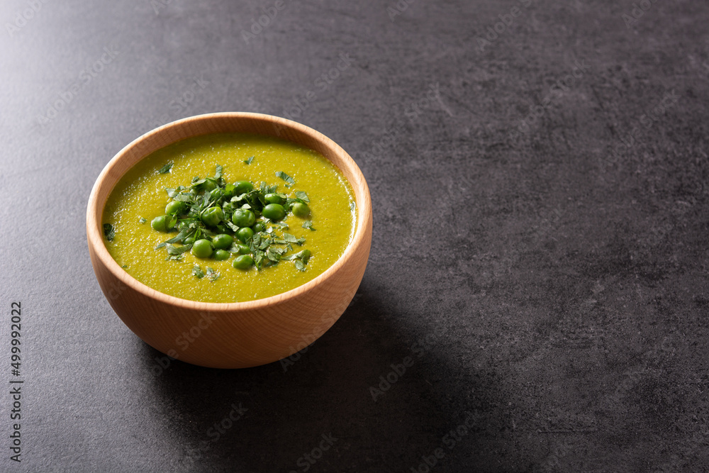 Green pea soup in a wooden bowl on black background. Copy space Green pea soup in a wooden bowl on black background. Copy space