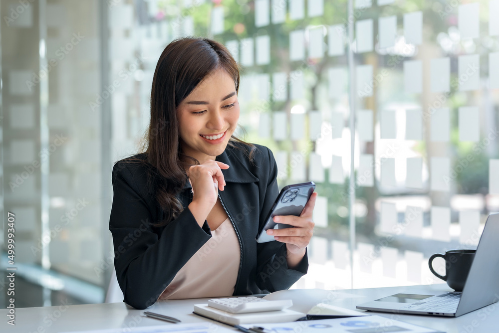 Asian business woman lightly smile when it's time to take a break with a smartphone at the office.