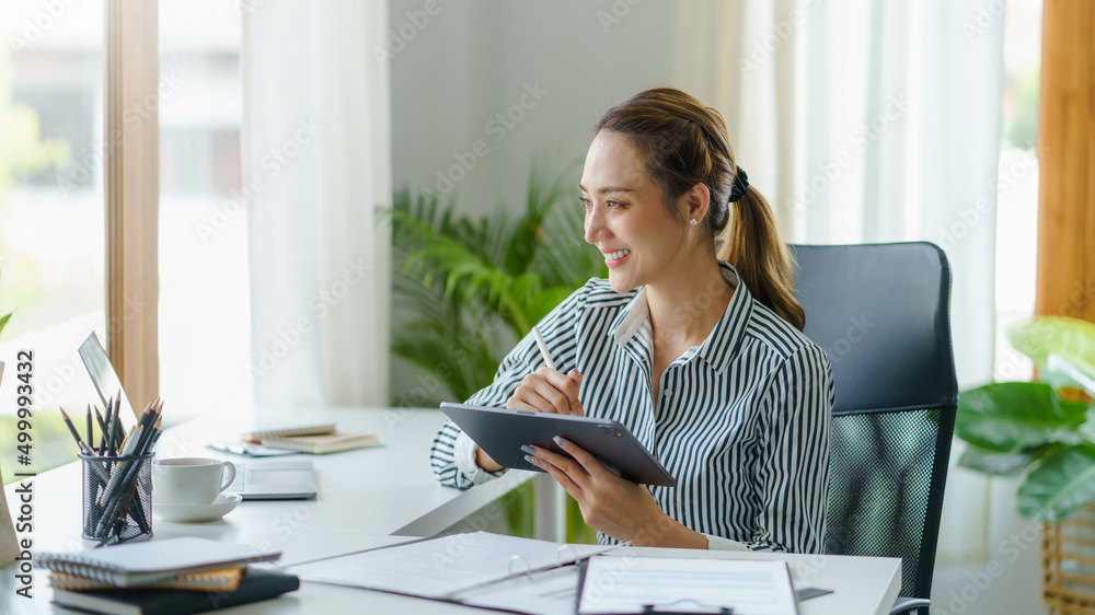 Happy Asian woman manager holding tablet in modern office Happy Asian woman manager holding tablet in modern office