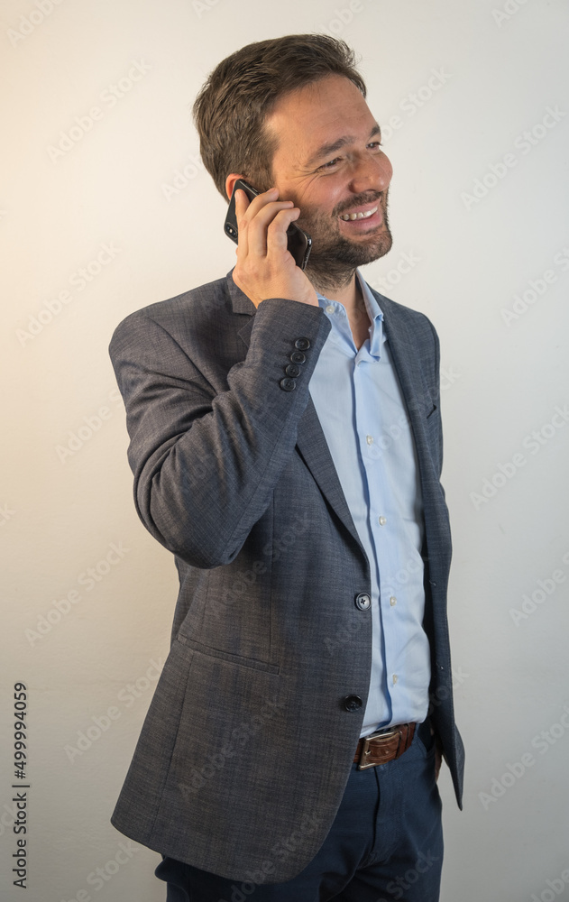 Handsome middle-aged businessman, wearing suit, making a phone call. Isolated. Neutral background. Handsome middle-aged businessman, wearing suit, making a phone call. Isolated. Neutral background.