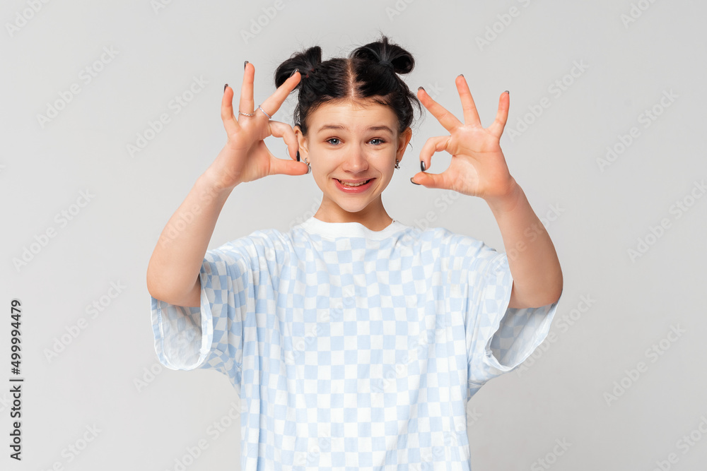 Φωτογραφία Cute dark-haired girl, schoolgirl teen showing okay, ok approval gesture, recomm