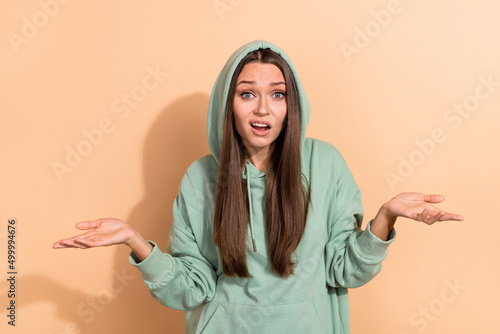 Portrait of attractive funky puzzled girl shrugging shoulders what why ask isolated over beige pastel color background photo