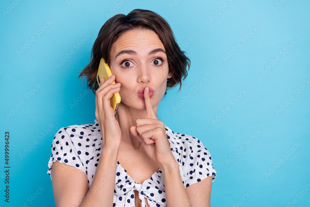 Photo of pretty girl speak communicate telephone finger touch lips shh isolated on blue color background Photo of pretty girl speak communicate telephone finger touch lips shh isolated on blue color background