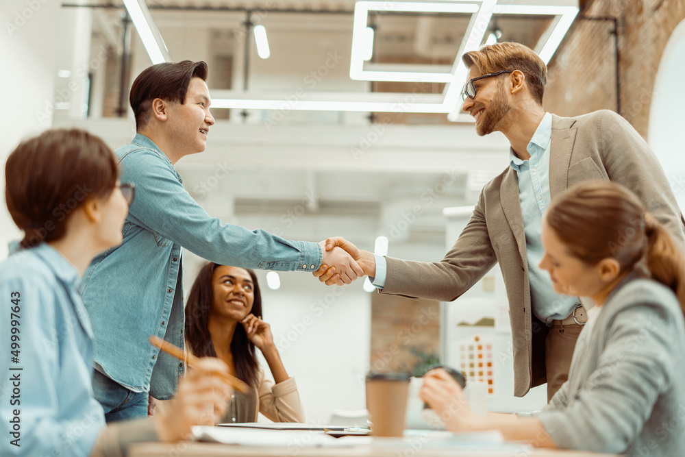 Two smiling men handshake in the office Two smiling men handshake in the office