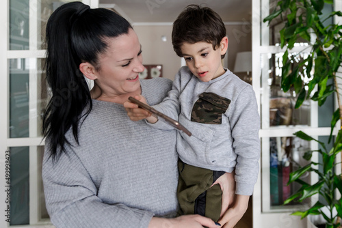 Disabled boy with autism in the arms of his smiling mother while being entertained with a mobile phone photo