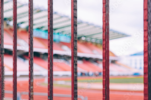 Closeup of a fence. Against the background of the stadium stands with a running track and a lawn. photo