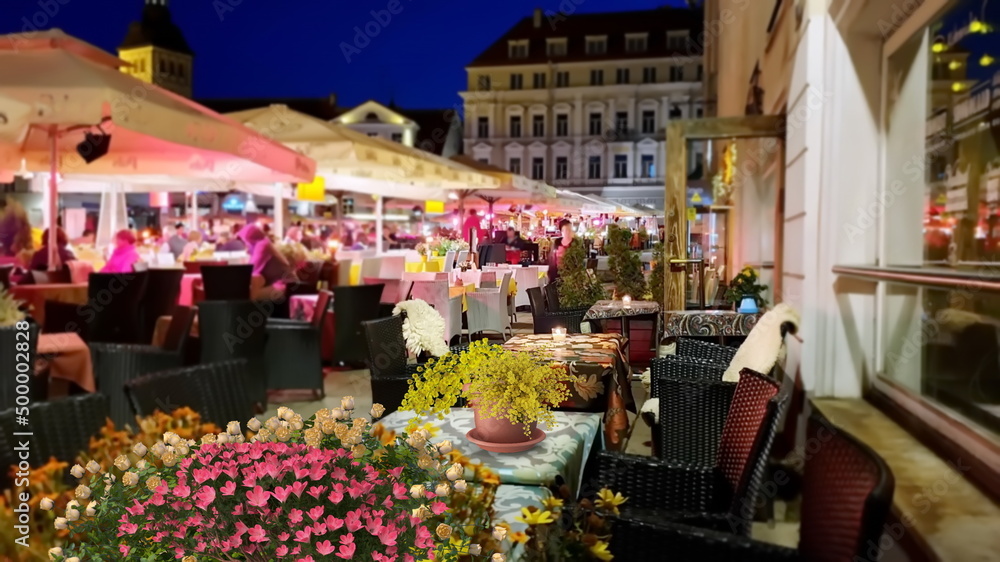  panorama   Summer City night life , Street cafe , City at  Summer  night life , Street cafe , Flowers cup with yellow flowers decoration ,evening bokeh blurring light , restaurant table, cup of coffe