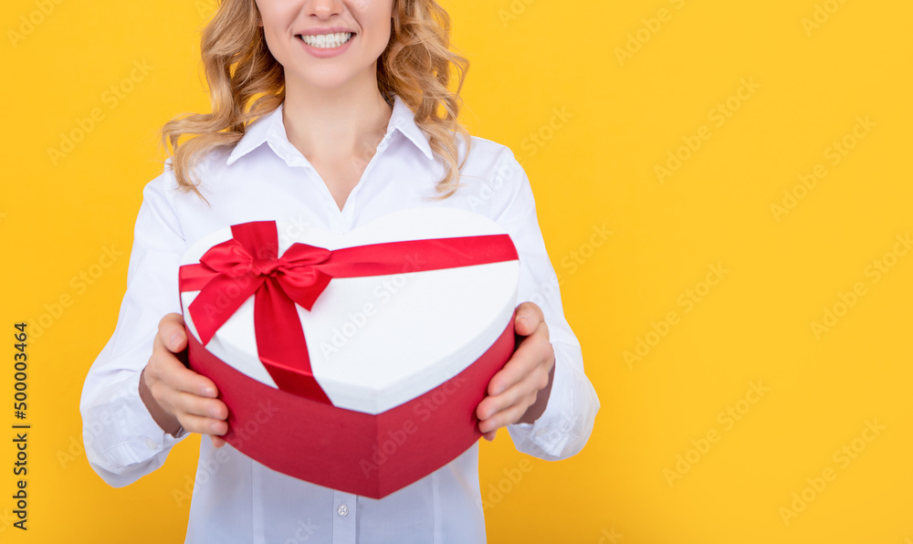 cheerful woman hold present heart box on yellow background cheerful woman hold present heart box on yellow background