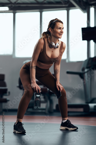 Pretty woman working out in a gym, making a pause. Adult pretty sporty lady with beautiful shaped body.