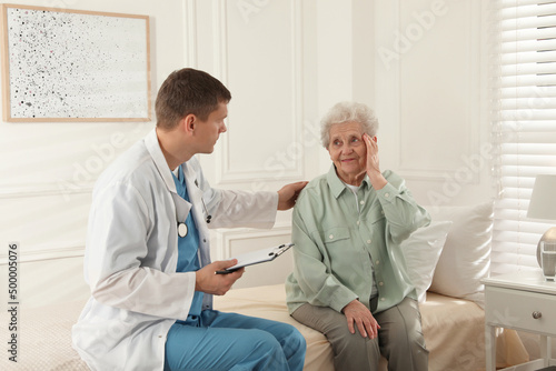 Caregiver examining senior woman in room. Home health care service