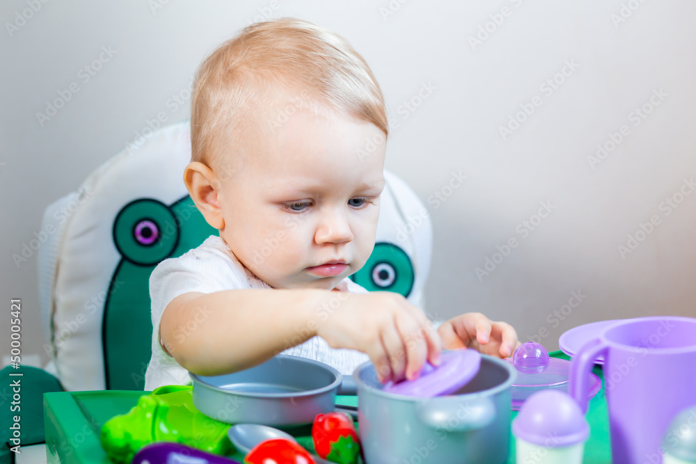 A little girl plays with toy vegetables on the background of children's dishes. A little girl plays with toy vegetables on the background of children's dishes.